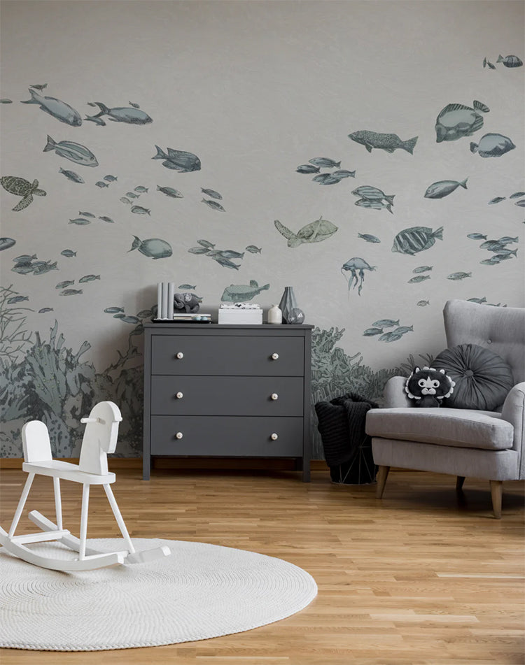 Under the Sea, Wallpaper in dusk blue creates a tranquil atmosphere that features a grey cabinet and a grey chair. A white wooden horse stands out, placed on a circular carpet that covers the wood flooring