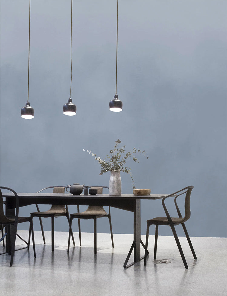 Watercolour Gradient Ombre Mural Wallpaper in Blue, featured on a wall of a modern dining area with a dark wooden table, metallic pendant lights.