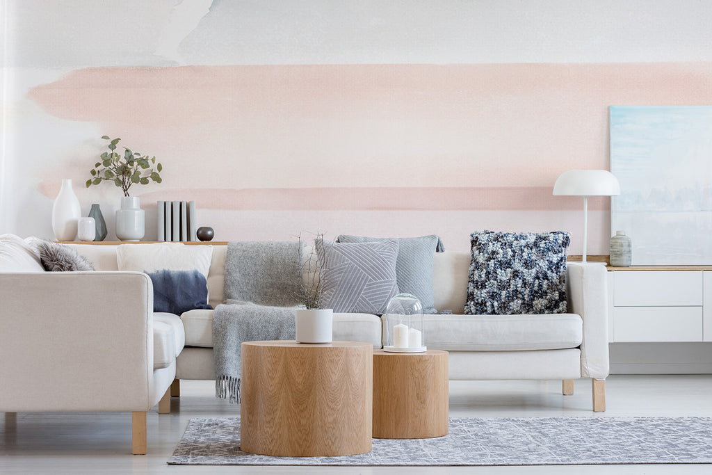 Modern living room with Watercolour Pastel Brushstrokes Mural Wallpaper, featuring a cozy sofa, wooden tables, and assorted decor creating a serene atmosphere.