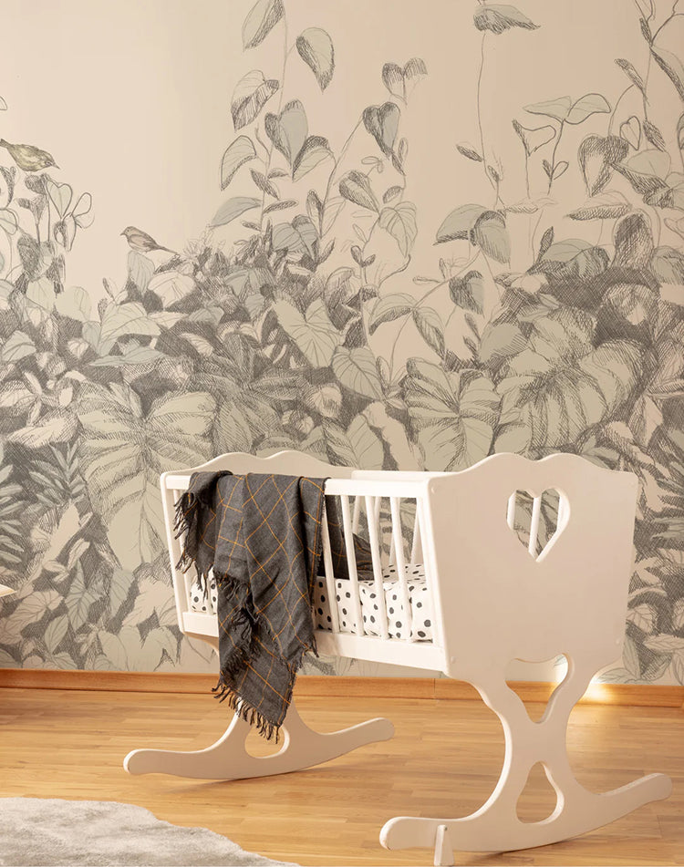 Willow Bush, Wallpaper in grey, graces a kid’s room wall. A white crib with a grey blanket is prominently featured.