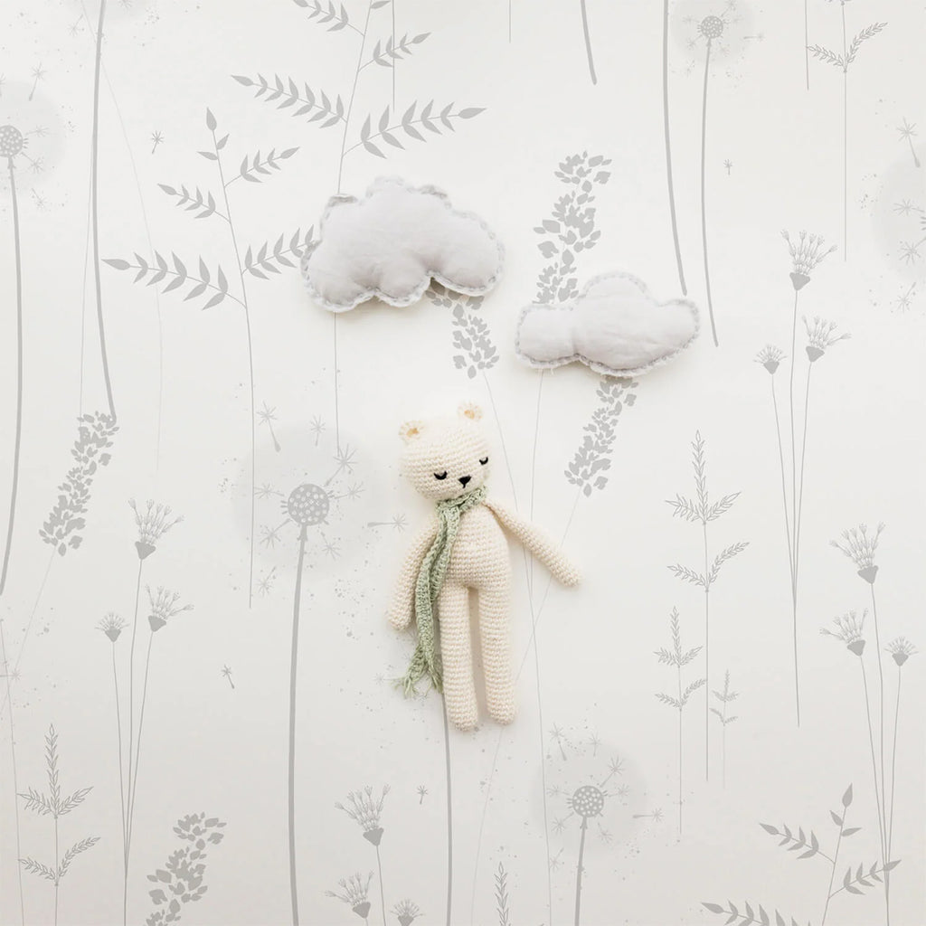 Plush cat toy with a green scarf against Willow Flower, Grey Pattern Wallpaper. The wallpaper has delicate grey floral and leaf designs. Two soft cloud-shaped decorations add to the serene atmosphere.
