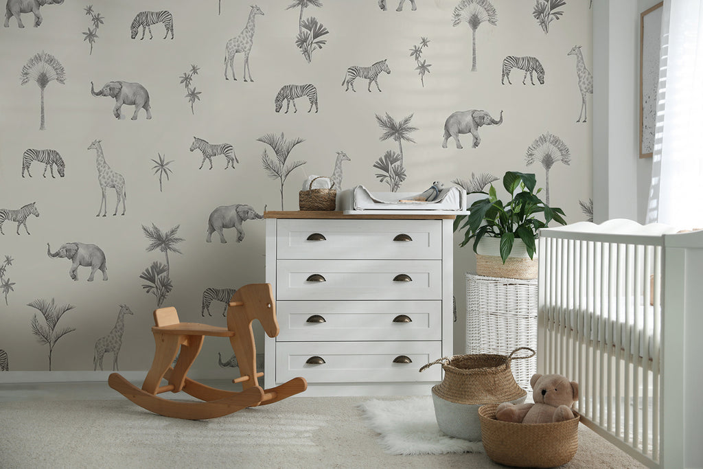 A serene nursery room adorned with Woodland Animals, Pattern Wallpaper in Black White, showcasing sketched elephants and zebras amidst foliage. A white crib, rocking horse, and other nursery essentials complement the whimsical decor.
