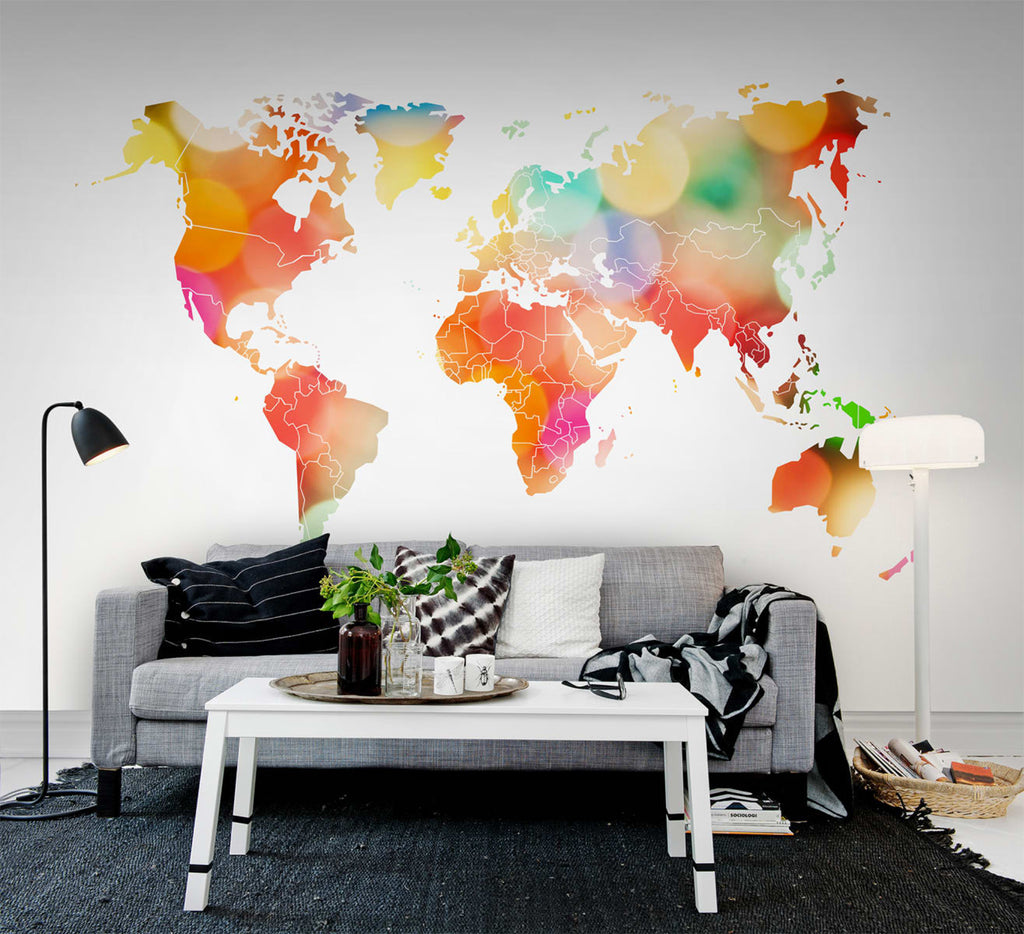 Your Own World Map, Mural Wallpaper in multicolor featured on a wall of a living area with grey sofa and black and white pillows and white table, with black floor mat