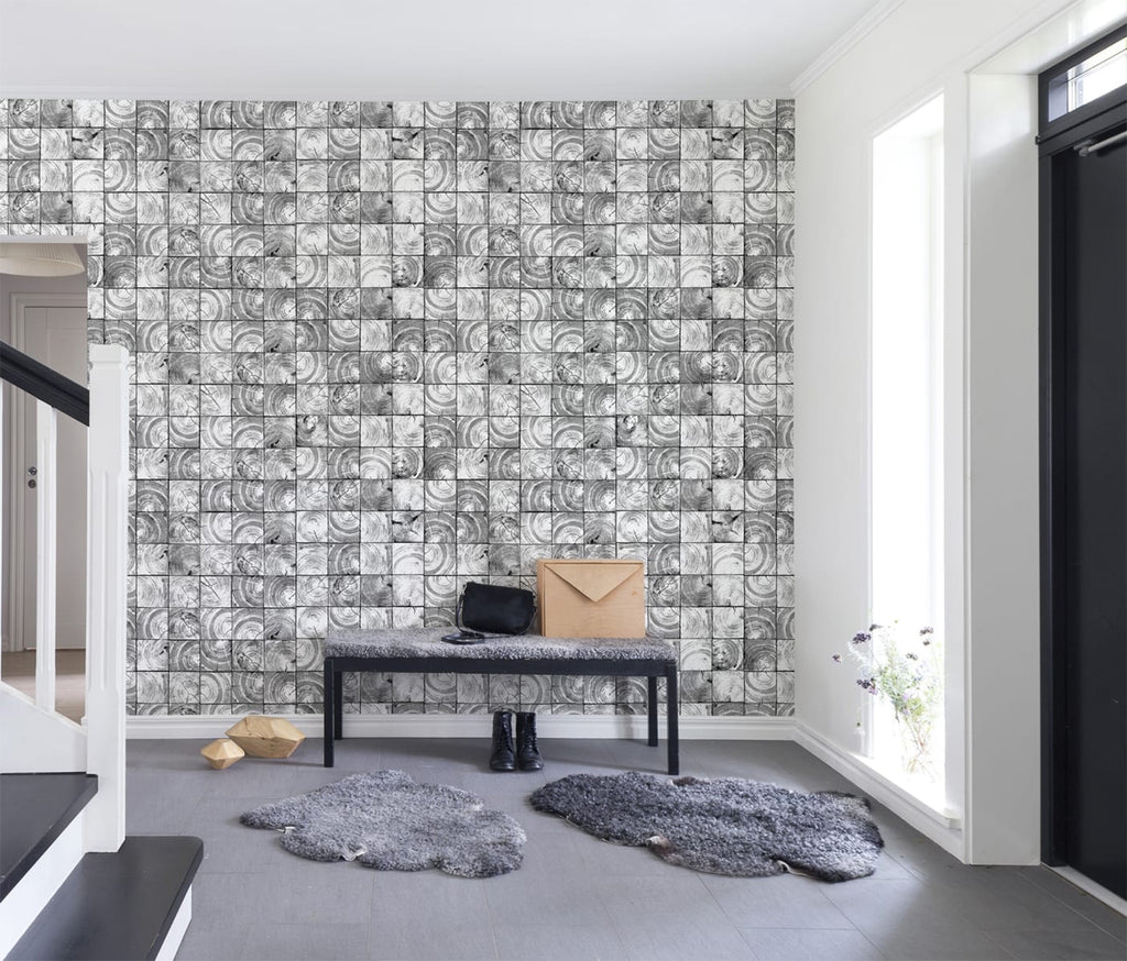 Green Reflection Patterned Wallpaper in black featured on a wall of a foyer with wooden flooring on it is a fluffy floor mat, a long chair with envelope and a bag