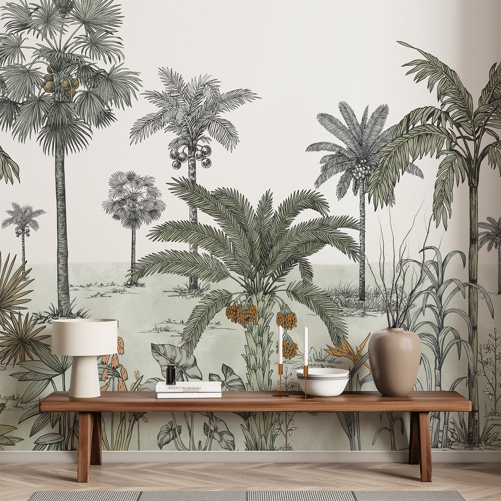 A hallway adorned with the Vintage Palmscape, Tropical Mural Wallpaper in Green. The monochrome mural depicts various palm trees and tropical foliage. The minimalist decor includes a wooden bench, a woven basket, potted plants, and a large window that bathes the space in natural light.