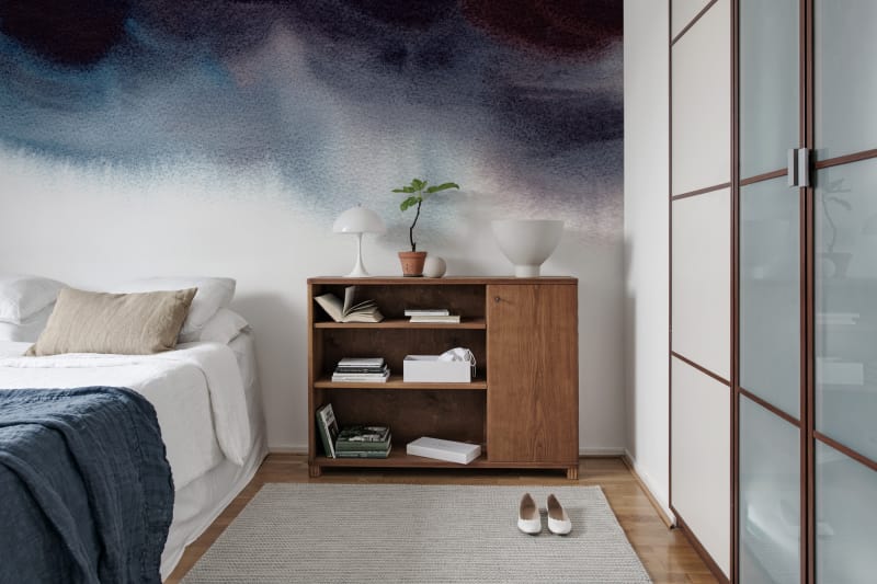 Merlina, Ombre Mural Wallpaper, featured in a comfortable bedroom having a wood flooring and wood bed-side cabinet. 