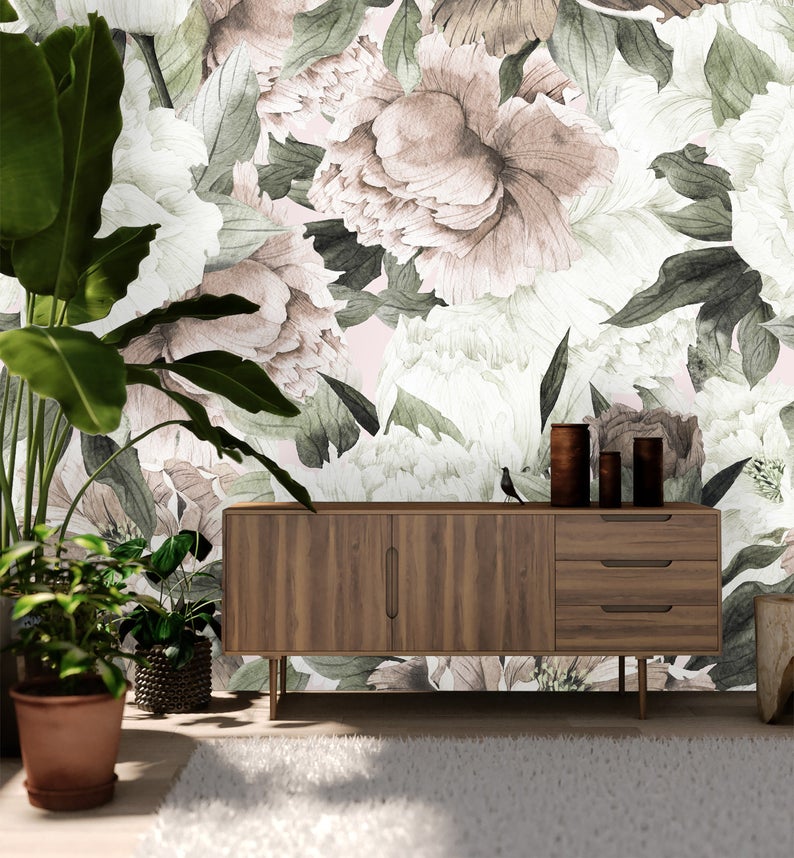 Tilda Vintage Roses Mural Wallpaper takes center stage in a room featuring a wooden console cabinet table and is beautifully surrounded by planters, evoking a charming botanical aesthetic.