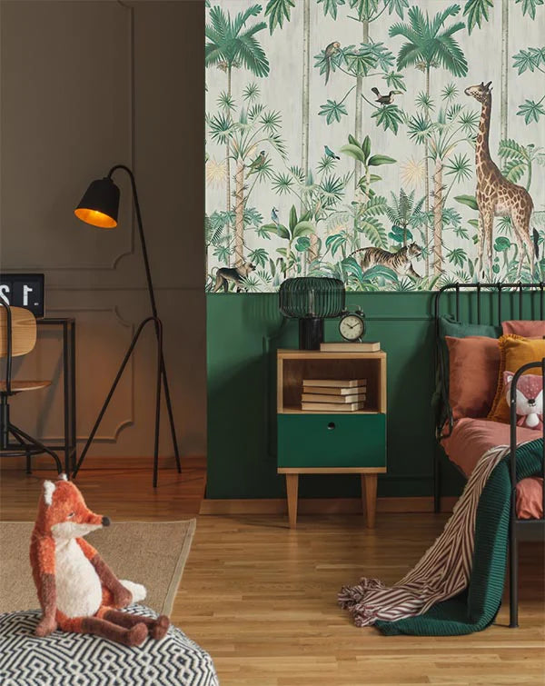 A Walk in the Jungle wallpaper with giraffes and palms in botanical illustration above deep green panelling beside a black floor lamp