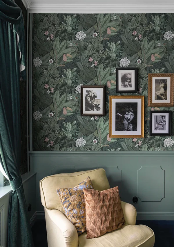 Furada Floral and Toucan jungle pattern wallpaper with toucans and pastel blossoms on deep green above panelling with a framed gallery wall